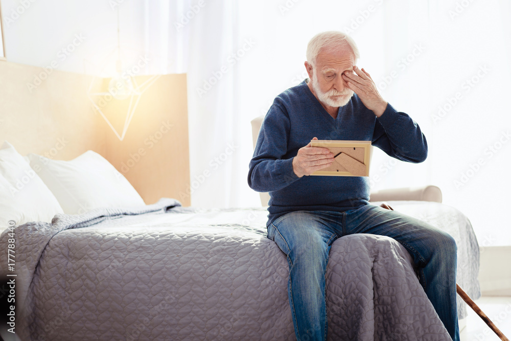 Poor senior man crying while remembering wife