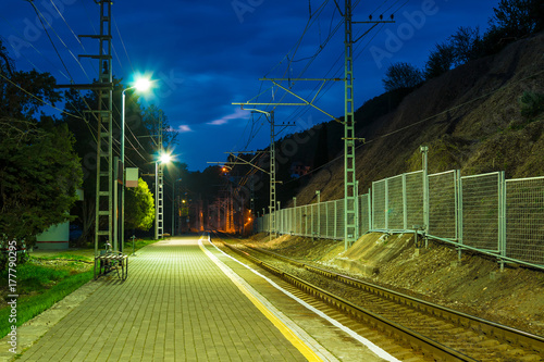 The illuminated platform of railway station and the railroad going into the distance at twilight, Sochi, Russia