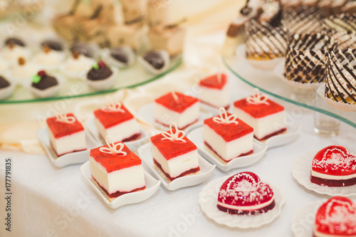 Delicious and tasty dessert table with cupcakes shots at reception closeup