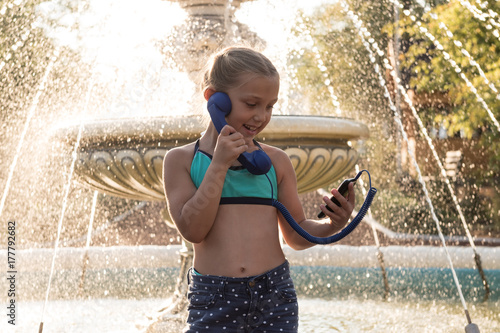 A young girl is happy with the good news that she was informed by the smartphone .. Against the background of a fountain located on the avenue leading to the sea. The resort town of Pyatimorsk. photo