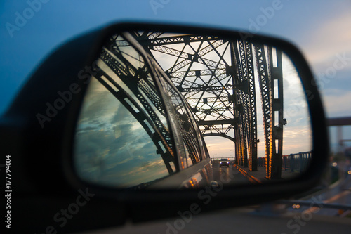 Car mirror reflection with view on bridge
