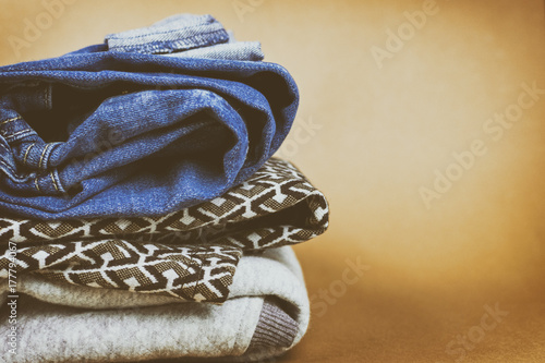 Warm and fashionable women's denim clothing folded on a colored background.