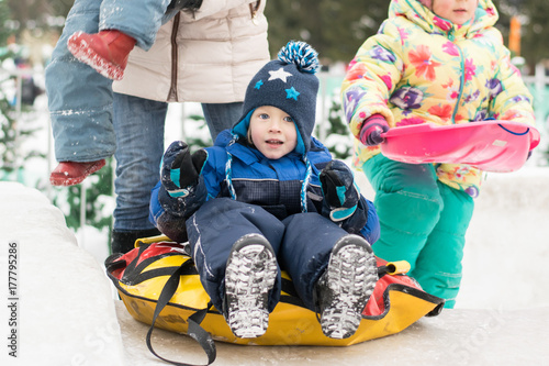 Obraz na płótnie Happy boy toboggan from a snow slide on colorful tube w salonie