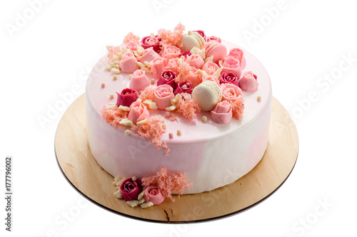 Pink glazed cake with cream flowers isolated on white