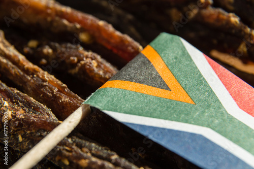 A close up image of a small South African flag on top of slices of biltong (dry meat) which is a traditional South African food snack.