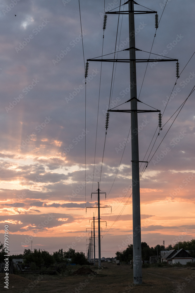 Power transmission line supports leaving the horizon on a sunset background. Concept of electricity.