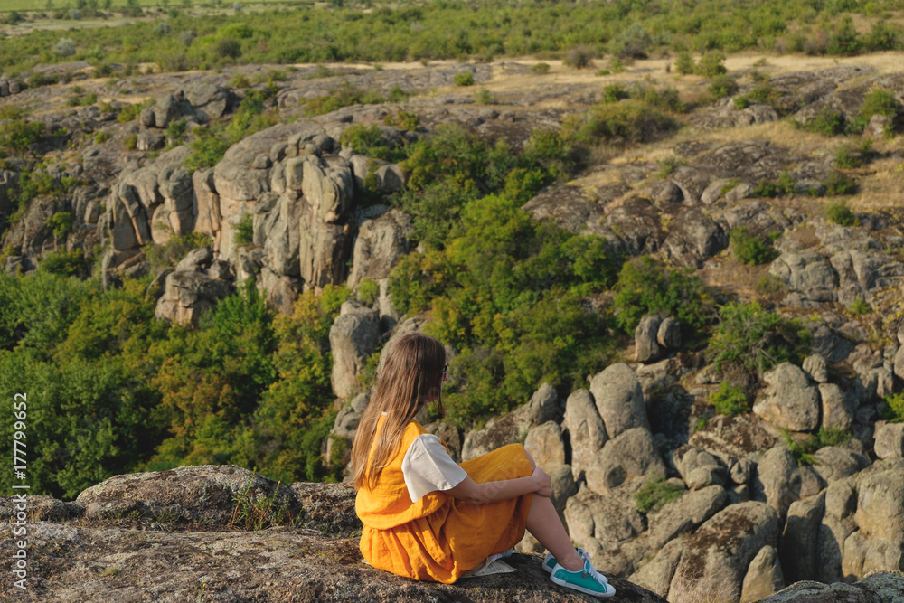 happy young girl sits on a background of the canyon