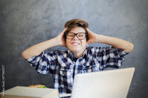 Teen boy holding his head a...