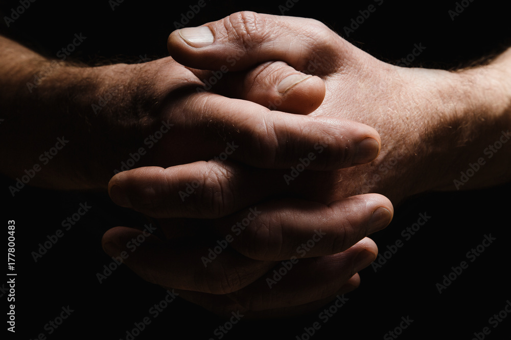 Hands of an elderly man's palms together, thought about problems, with dramatic lighting