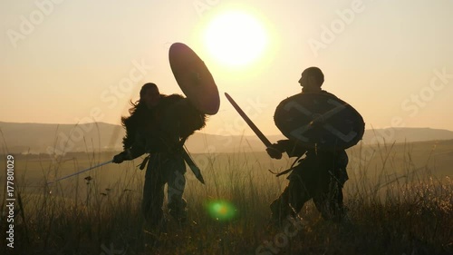 Silhouettes of warriors Viking are fighting with swords and shields. Contre-jour photo