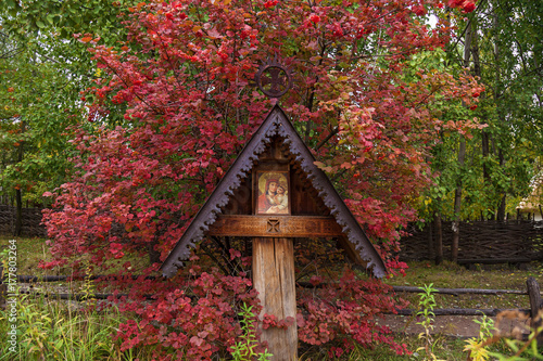 The Icon a Mother of God Mary and child Jesus Christ, old Orthodox icon under an old canopy next to a bush of red viburnum © Oleg