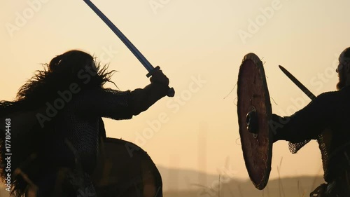 Silhouettes of warriors Viking are fighting with swords and shields. Contre-jour