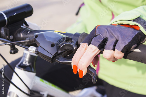 Woman's hand with bright nail Polish on the Bicycle wheel.