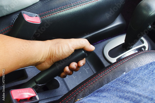 Man's hand pulling handbrake lever in the car