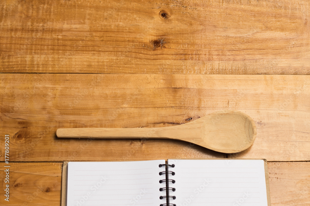 Copy space open book and spoon on wooden table, kitchen presentation