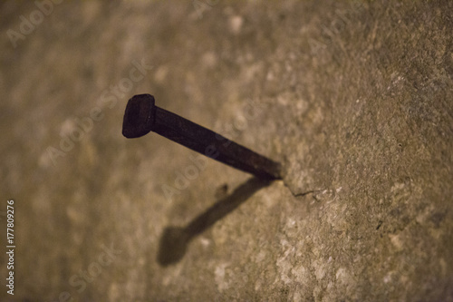in a light brown wall a large, rusty nail