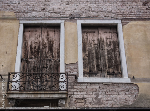 house detail with shutters on windows in venice balcony cracked plaster yellow wall and elegant crumbling ancient brickwork