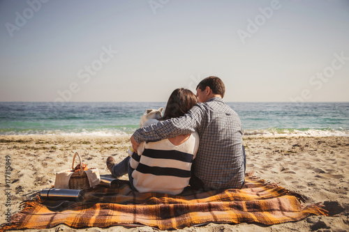 Young happy loving family with small child, enjoying time at beach sitting and hugging near ocean, happy lifestyle family concept