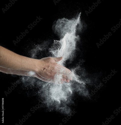Freeze motion of dust explosion in hands isolated on black background