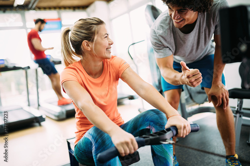 Obraz na plátně Young beautiful woman doing exercises with personal trainer