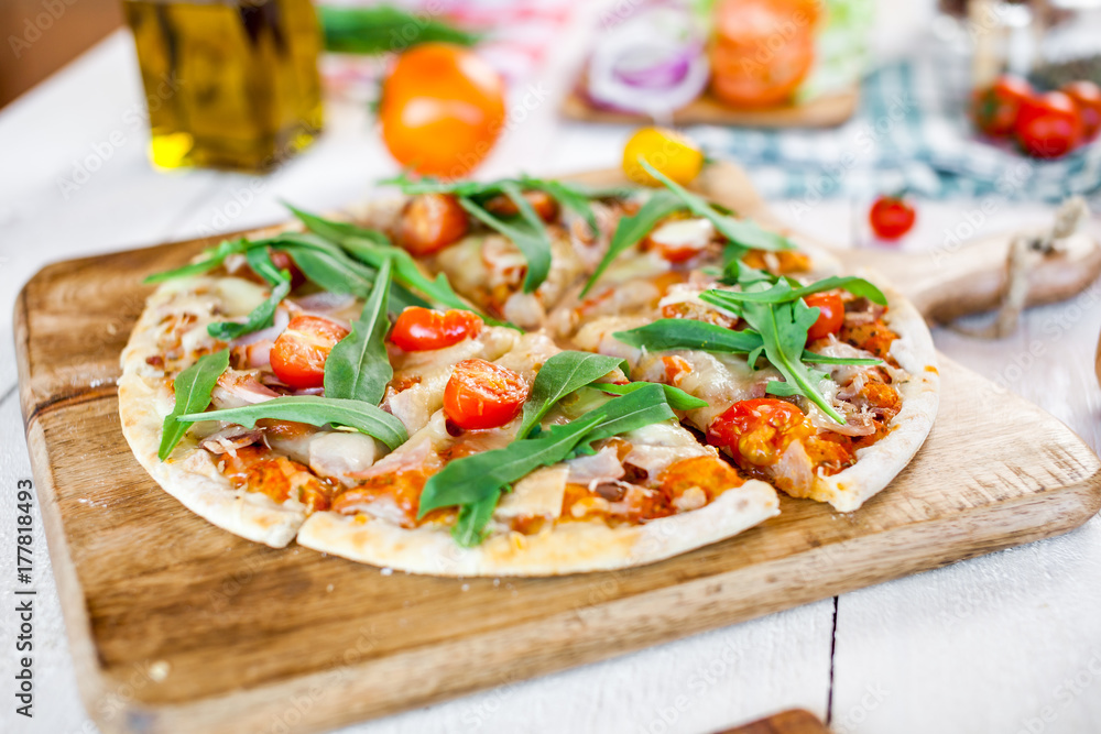hot fresh homemade traditional italian pizza with cheese, tomatoes and rocked salad on wooden cooking table. wallpaper for pizzeria and food concept hot fresh homemade traditional italian pizza with cheese, tomatoes and rocked salad on wooden cooking table. wallpaper for pizzeria and food concept