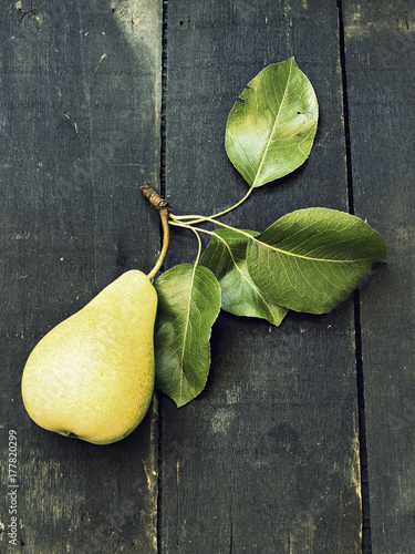 Billede på lærred Just picked a pear on a dark wooden surface - vintage look