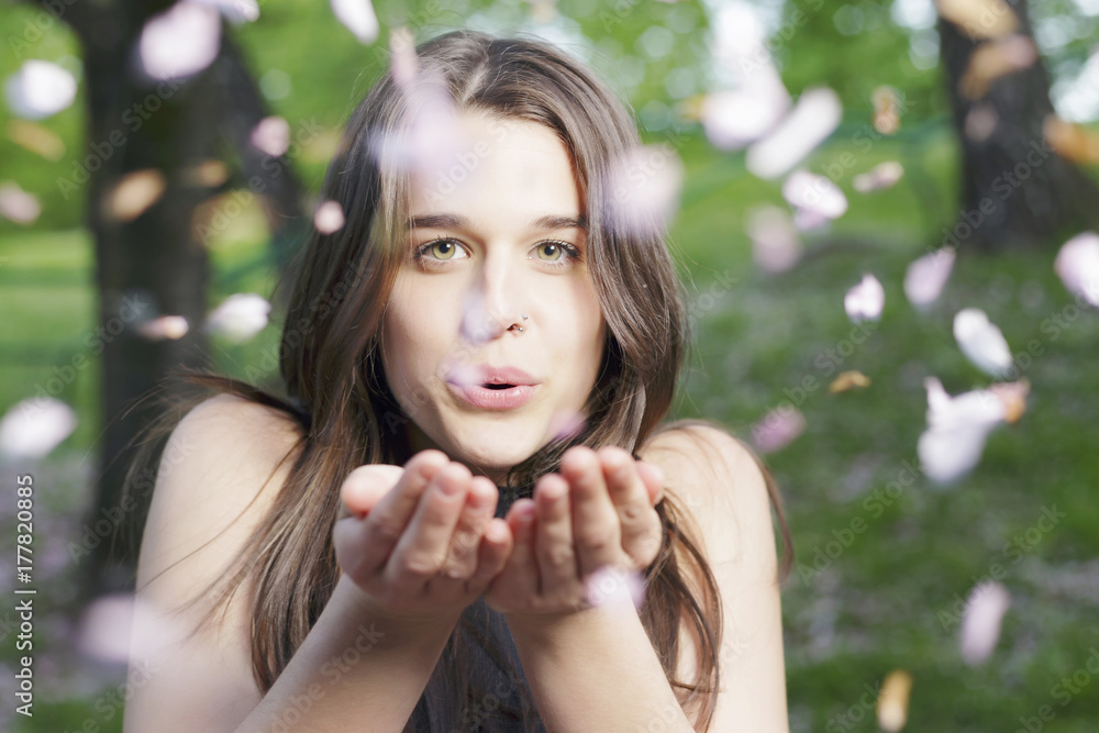 Beautiful girl blowing a handful of flowers, outdoors, in a spring park. Beautiful girl blowing a handful of flowers, outdoors, in a spring park.