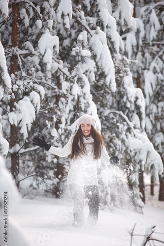 Happy woman on the winter background. Young pretty girl in the woods outdoors. Portrait of a cheerful beautiful woman.