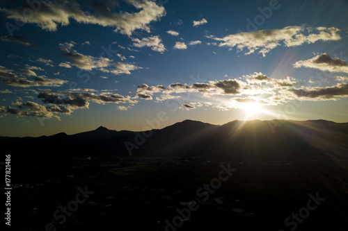 Aerial view of a silhouette of a mountain and a cloudy sky during the sunset.