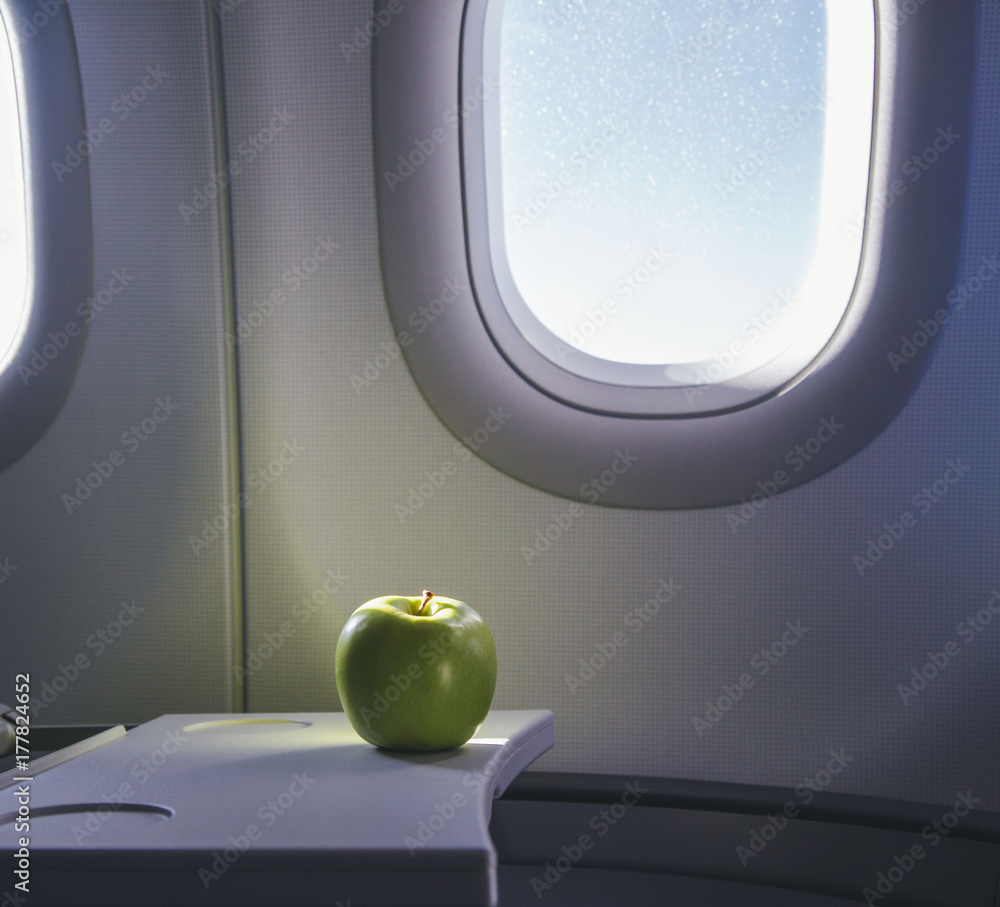Fototapeta premium a green apple on the table of airplane