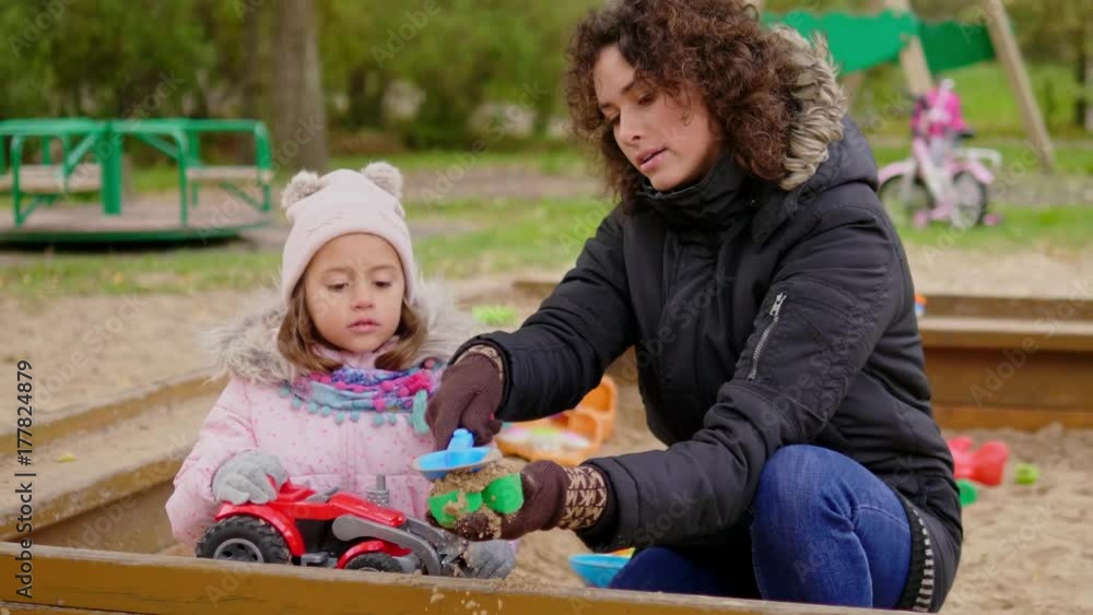 Mother playing with her daughter in a sandbox Mother playing with her daughter in a sandbox