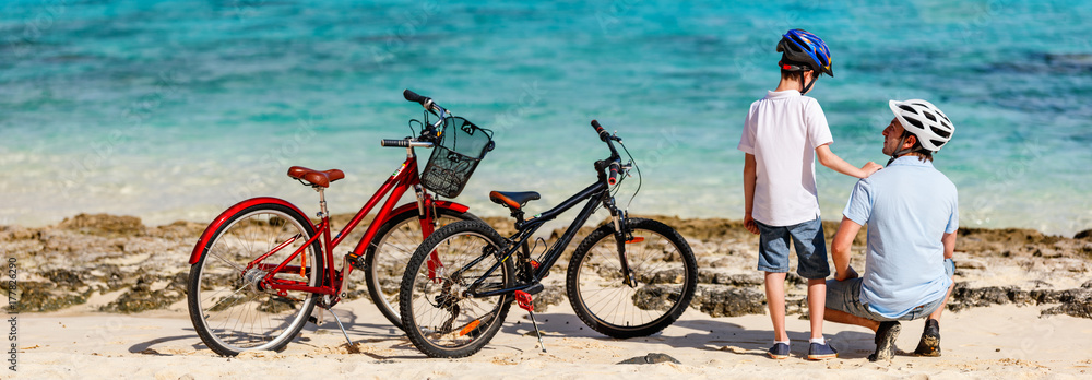 Naklejka premium Father and kids at beach with bikes