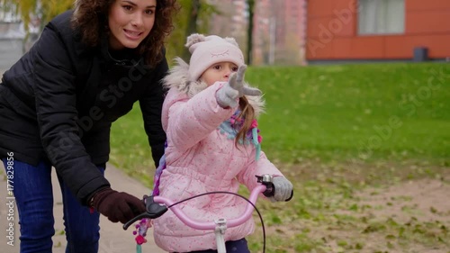 Mother teaching daughter to ride a bicycle photo