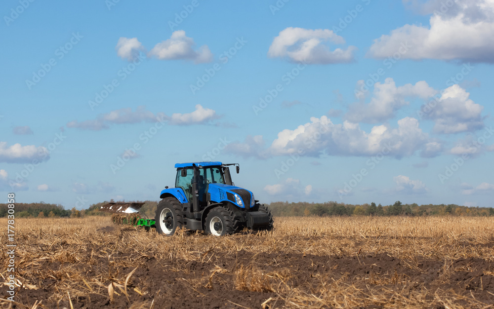a large blue tractor, plowing field against the beautiful sky. Work of agricultural machinery. Harvest a large blue tractor, plowing field against the beautiful sky. Work of agricultural machinery. Harvest