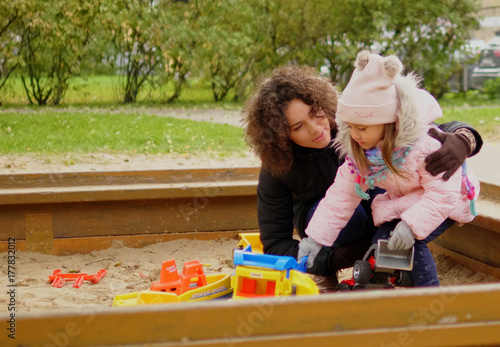 Mother playing with her daughter in a sandbox photo