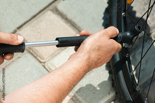 Top view of the man is pumping a bike wheel on the street.