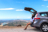Woman traveler sitting on hatchback car with mountain background