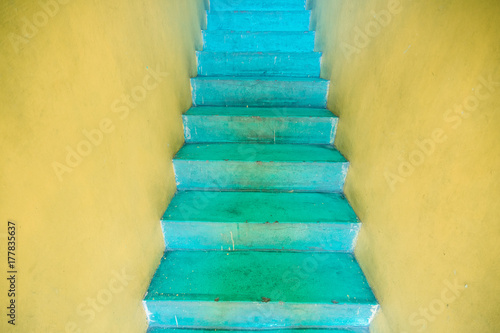 Bright yellow entrance with surreal turquoise colored stairs photo