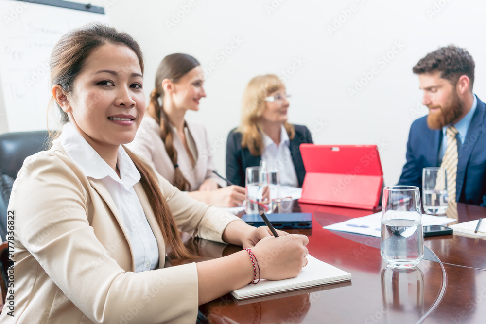 Portrait of a confident Asian business woman wearing formal outfits while sitting down during a decision-making meeting, in the conference room of a successful company Portrait of a confident Asian business woman wearing formal outfits while sitting down during a decision-making meeting, in the conference room of a successful company