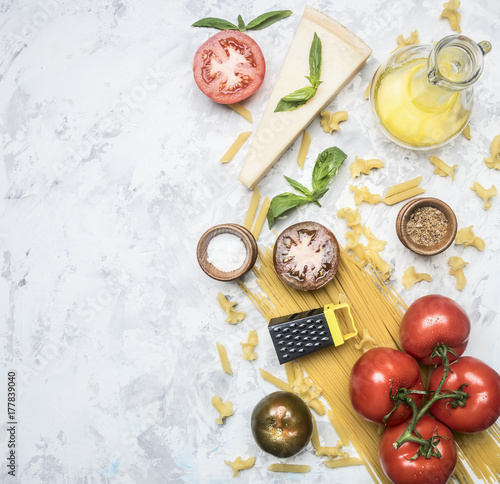 concept of cooking Italian spaghetti pasta with tomatoes, parmesan, basil, butter and seasonings, ingredients lined up on a white rustic background, space for text, top view