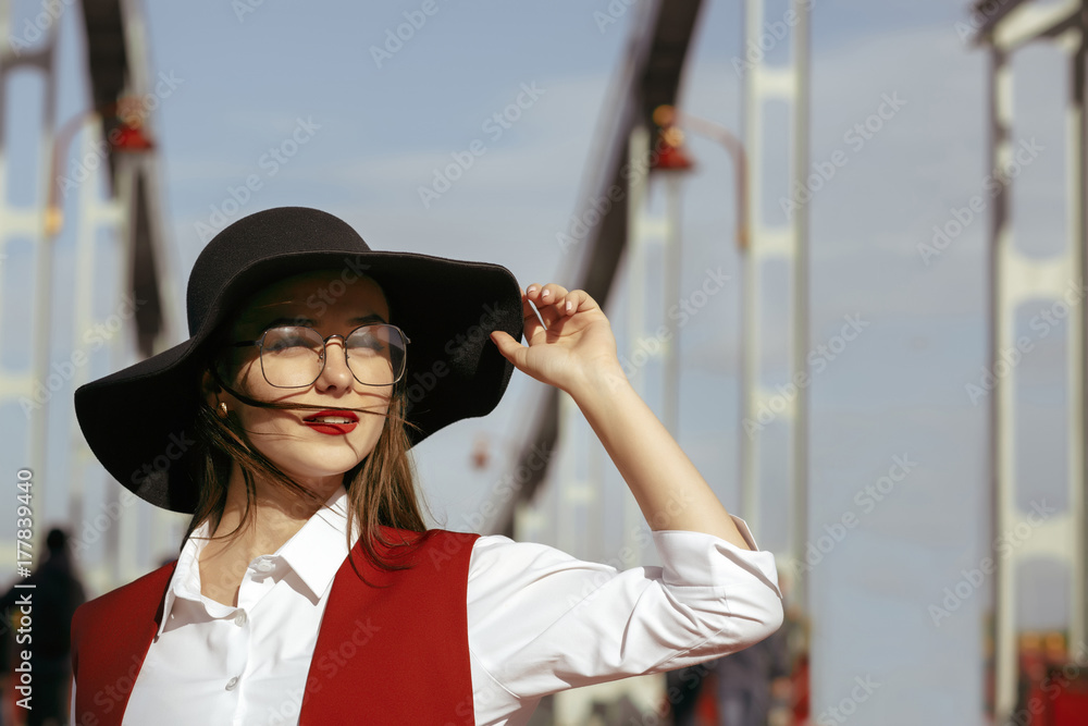 Fashion portrait of stylish model wears red costume, black hat, stylish glasses. Empty space