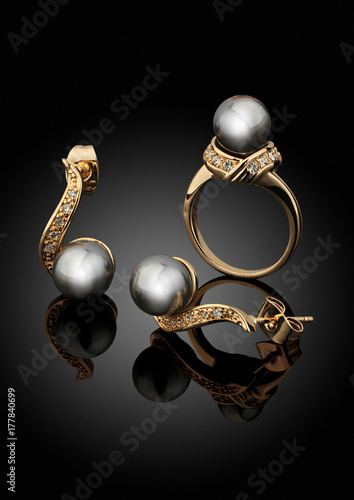 Golden jewelry set with pearls on black background with reflection