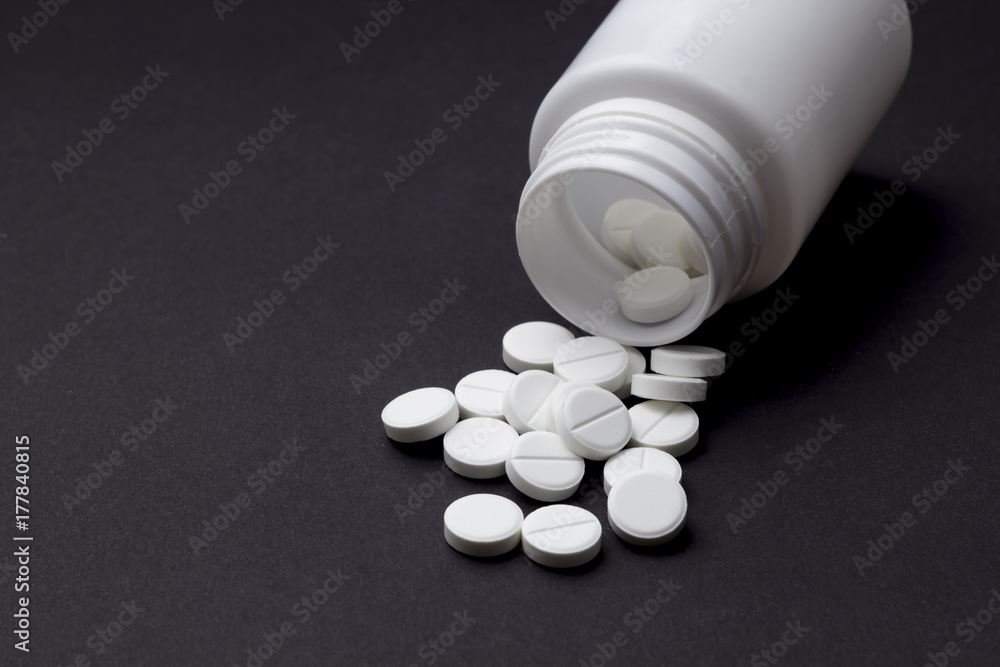 Tablets on a black background. Capsules with a jar.