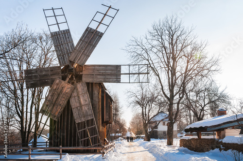 A traditional windmill on a snow-covered street at the open-air Village Museum in Bucharest, Romania.