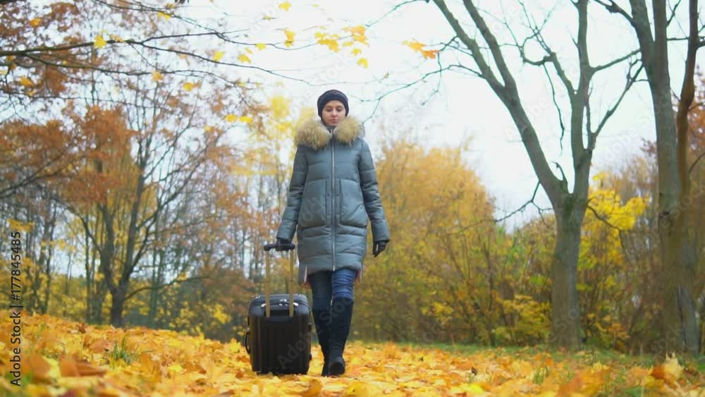 Woman with a suitcase in an autumn park Woman with a suitcase in an autumn park