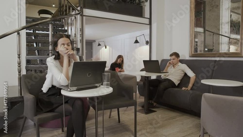 Young girl drinks water beacuse of headache of working on the laptop photo