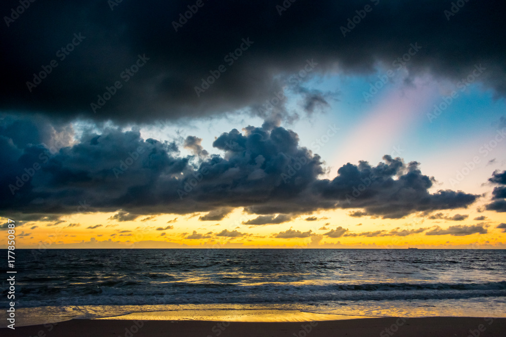 Fototapeta premium colored cloud layers over the ocean on a warm morning at the beach