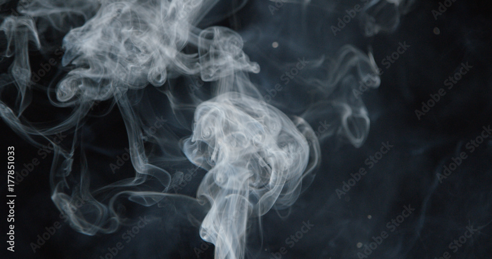 Fototapeta premium Puffs of white smoke over dark background