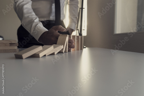 Retro image of a businessman stopping the domino effect with a sunlight