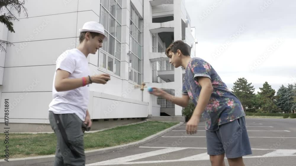 Two kids having a kendama contest in the schoolyard Two kids having a kendama contest in the schoolyard